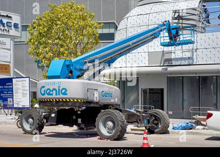 Genie Teleskopausleger-Hubmaschine mit Wiege und Sicherheitskorb für Männer, die über dem Dachabschnitt eines Neubaus arbeiten Stockfoto