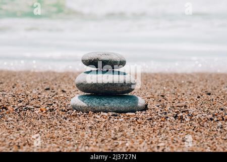 Felsbalancierung am Meeresstrand. Kieselsteinpyramide an sandigen Ufern. Stabiler Stapel oder Haufen im weichen Fokus mit Bokeh, Nahaufnahme. Zen-Balance, Minimalismus, har Stockfoto