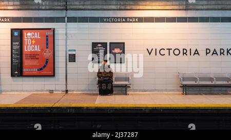 Eine muslimische Frau sitzt auf einer Bank und wartet auf einen TTC-U-Bahn-Zug auf dem Bahnsteig der Victoria Park U-Bahn-Station. Weitwinkelansicht. Die Toronto Transit Commi Stockfoto