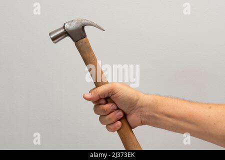 Die Hand des Mannes hält ein auf grauem Hintergrund isoliertes Werkzeug. Stockfoto