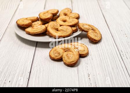 Palmier Blätterteig Kekse in weißem Teller auf einem weiß gestrichenen Holztisch Stockfoto