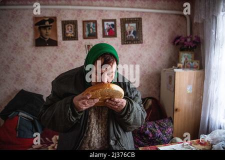 Borodyanka, Ukraine. 05. April 2022. Eine ältere Frau riecht Brot, das ihr von Freiwilligen in ihrem Haus in Irpin gebracht wurde, das durch Schübe beschädigt wurde. Russland marschierte am 24. Februar 2022 in die Ukraine ein und löste damit den größten militärischen Angriff in Europa seit dem Zweiten Weltkrieg aus (Foto: Laurel Chor/SOPA Images/Sipa USA) Quelle: SIPA USA/Alamy Live News Stockfoto