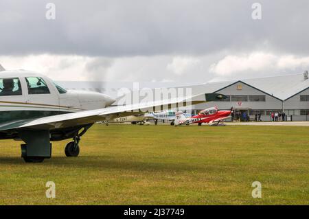 Leichte Flugzeuge vor dem Lotsenschlaf und den Gebäuden des Sywell Aerodrome, Northamptonshire, Großbritannien, bereit für ein Rennen im Royal Aero Club. Stockfoto