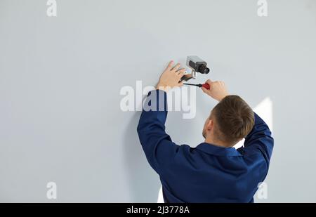 Ein professioneller männlicher Techniker montiert eine Videoüberwachungskamera an der Wand des Hauses oder Büros. Stockfoto