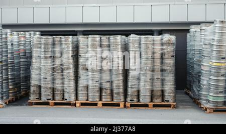 Bierkegs. Viele Metallfässer oder Behälter für Brauereien in Paletten im Freien gestapelt. Stockfoto