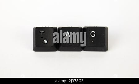 Tag-Text, der mit isolierten Tastaturtasten auf weißem Hintergrund erstellt wurde, weißer Tag auf schwarzer Tastatur, Draufsicht Stockfoto