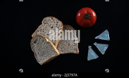 Brotscheiben und rote Tomate mit Dreieckskäse, auf Tisch legen, Lebensmittel konsept, Brotscheiben mit Tomate isoliert auf schwarzem Hintergrund, Draufsicht Stockfoto