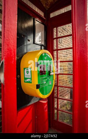 Ein Notfall-Herzdefibrillator in einer umgewandelten roten Telefonbox in Großbritannien Stockfoto