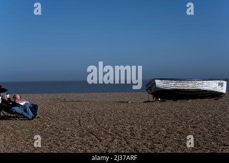 Ein älteres Paar, das am Strand von Aldeburgh in Suffolk in England schläft Stockfoto