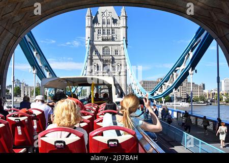 Rückansicht Frauen auf Doppeldeckerbus mit offenem Oberdeck in London unter dem Bogen der historischen Tower Bridge Road über die Hochflut der Themse England Stockfoto
