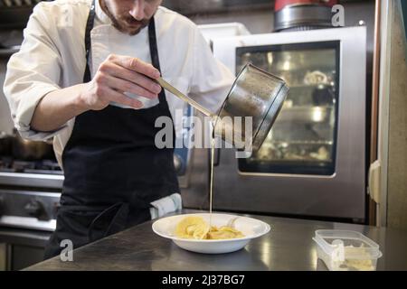 Blick auf einen professionellen Koch, der frische hausgemachte italienische Tortellini-Pasta in der Küche serviert Stockfoto