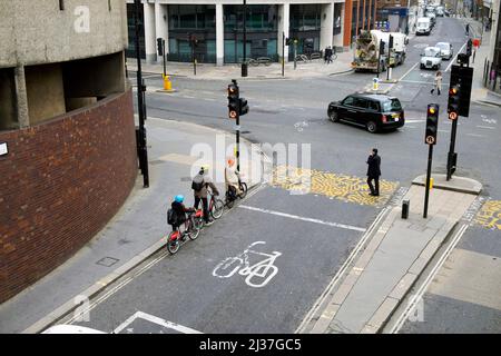 Familie wartet auf Fahrräder mit Schutzhelmen Radfahrer warten an der Ampel auf der Beech Street und Aldersgate in der City of London UK KATHY DEWITT Stockfoto