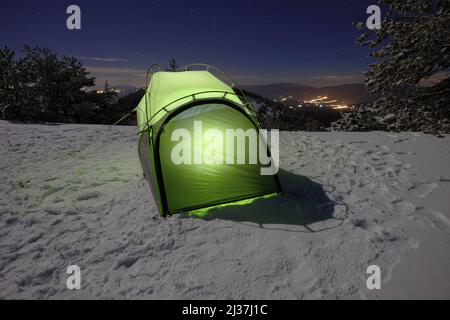 Beleuchtetes grünes Zelt auf dem Schnee in der Nacht im Ätna Park, Sizilien Stockfoto