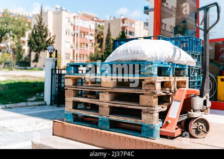 Leere Paletten außerhalb des Lagers. Holzpaletten auf einem Hydraulikwagen. Lagereinrichtungen. Ausverkaufte Rohstoffe während eines Panikkaufes. Warendefizit Stockfoto