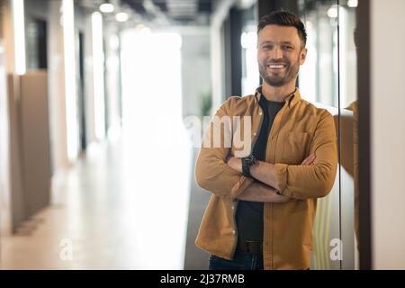 Glücklicher Geschäftsmann, Der In Doorway Of Modern Office Steht Stockfoto