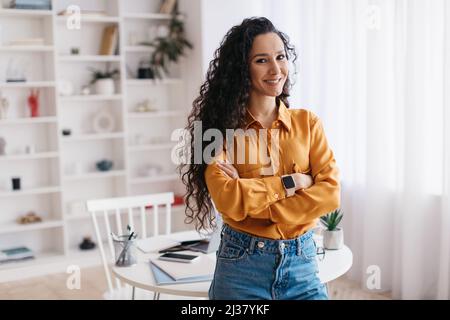 Brunette Lady Überquert Die Hände Lächelnd Zur Kamera Stehend Im Innenbereich Stockfoto
