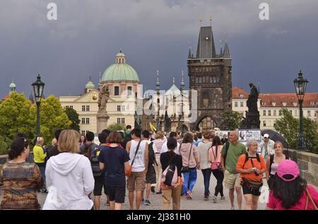 Touristen, die über die Karlsbrücke und die historischen Türme der Altstadt in Prag, Tschechien, wandern. Stockfoto