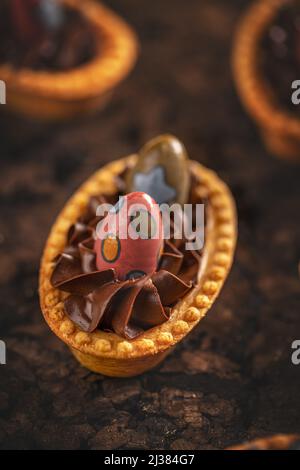 Köstliches Tartlets-Dessert mit Schokoladencreme-Füllung, verziert mit Mini-Osterschokolade-Eiern Stockfoto
