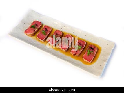 Ein Blick von oben auf das traditionelle japanische Thunfisch-Tataki-Essen auf einem Teller, der auf weißem Hintergrund isoliert ist Stockfoto