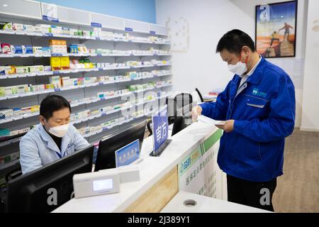 Shanghai, China. 5. April 2022. Der Deliveryman Ye Yifei (R) gibt einem Arzt Rezepte zur Überprüfung in der Shanghai Pharma E Pharmacy in Shanghai, Ostchina, 5. April 2022. Während der vorübergehenden geschlossenen Behandlungsdauer in Shanghai ist die Versorgung und Lieferung von Spezialmedikamenten an die Patienten, die diese benötigen, besonders wichtig. Eine Apotheke namens Shanghai Pharma E Pharmacy, die mehr als 260 neue Medikamente, Spezialmedikamente und Medikamente für seltene Krankheiten verkauft, bleibt im Geschäft, um die Medikamente zu liefern und zu liefern. Quelle: Jin Liwang/Xinhua/Alamy Live News Stockfoto