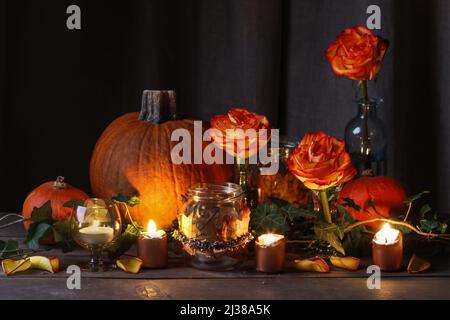 Herbsthochzeit Dekoration mit Kürbissen, Orangenrosen und Kerzen. Partydekor Stockfoto