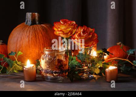 Herbsthochzeit Dekoration mit Kürbissen, Orangenrosen und Kerzen. Partydekor Stockfoto