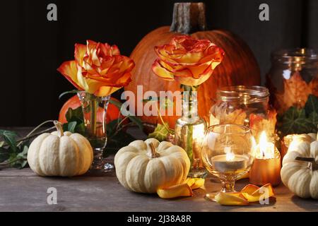 Herbsthochzeit Dekoration mit Kürbissen, Orangenrosen und Kerzen. Partydekor Stockfoto