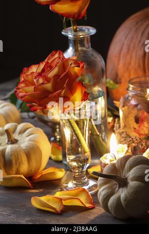 Herbsthochzeit Dekoration mit Kürbissen, Orangenrosen und Kerzen. Partydekor Stockfoto