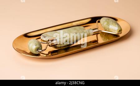 Gua Sha Massage Jade Werkzeuge. Abstreifer und Rolle auf goldenem Ständer. Lifting, Toning und Anti-Age-Behandlung. Beauty- und Entspannungskonzept. Hochwertige Fotos Stockfoto