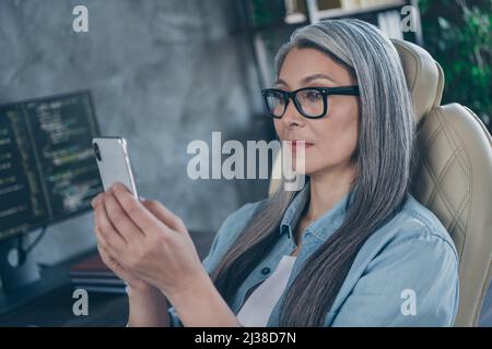 Porträt einer attraktiven, intelligenten, fokussierten, grauhaarigen Codierin, die die Geräte-Gadget-App auf der Arbeitsstation in Innenräumen verwendet Stockfoto