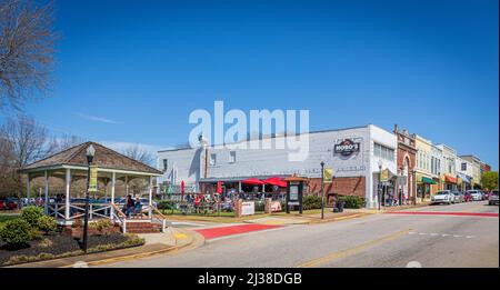 FORT MILL, S.C., 2. APRIL 22: Weitwinkelansicht der Main Street mit Bewohnern, die den Frühling im Confederate Park genießen, und einer Reihe von Gebäuden in der Innenstadt. Stockfoto