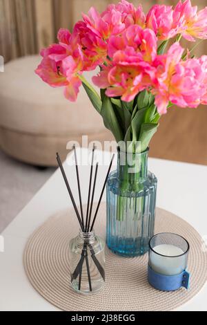 Aroma-Schilfdiffusor, Tulpen und Kerze auf dem Tisch zu Hause Stockfoto