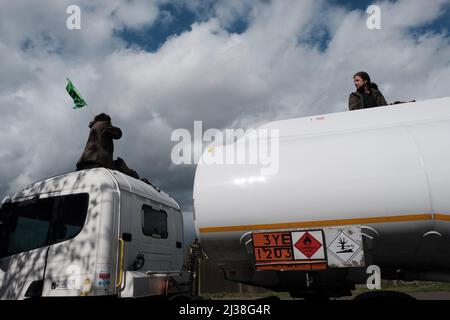 Staines, Großbritannien. 6. April 2022. Mitglieder des Extinction Rebellion besteigen die Tanker am Eingang zum Esso West London Terminal in der Nähe des Flughafens Heathrow. Die Demonstranten fordern ein Ende der fossilen Brennstoffe. Extinction Rebellion (XR) und Just Stop Oil blockieren seit dem Wochenende Straßen, die für den Zugang zu Ölraffinerien in der Nähe von London und Birmingham genutzt wurden, und verhindern, dass Tankwagen die Treibstoffdepots verlassen oder betreten. Stockfoto