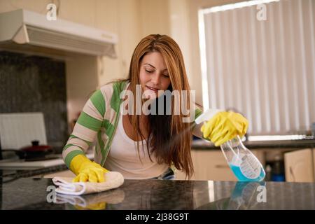 Sauber halten. Aufnahme einer jungen Frau, die eine Küchenarbeitsfläche putzt. Stockfoto