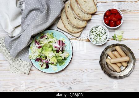 Frühstückstisch mit frischem Salat, Cottage, Brotscheiben und Würstchen. Gesunde Ernährung Stockfoto