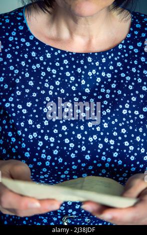 Frau in einem blauen Kleid, die einen Brief liest Stockfoto