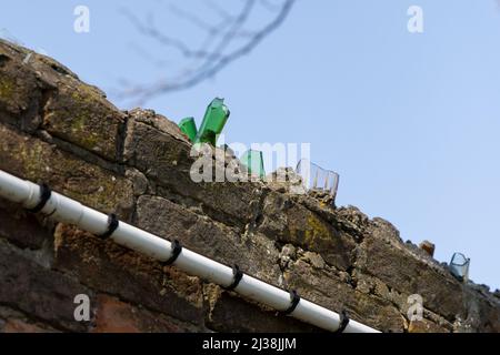 Zerbrochene Glasflaschen auf der Oberseite einer Wand; helfen, eine Abschreckung von Menschen zu schaffen, die die Wand klettern. Die alte Methode zum Schutz des Territoriums Stockfoto