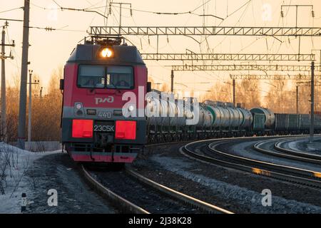 SHARYA, RUSSLAND - 19. MÄRZ 2022: Elektrische Lokomotive 2ES5K 'Ermak' mit Güterzug in einer Wendung am Märzabend. Northern Railway Stockfoto