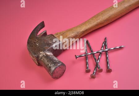 Hochwinkelansicht von Hammer und Nägel isoliert auf einem rosa Hintergrund Stockfoto