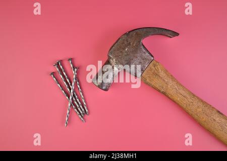 Flatlay-Ansicht von Hammer und Nägel isoliert auf einem rosa Hintergrund Stockfoto