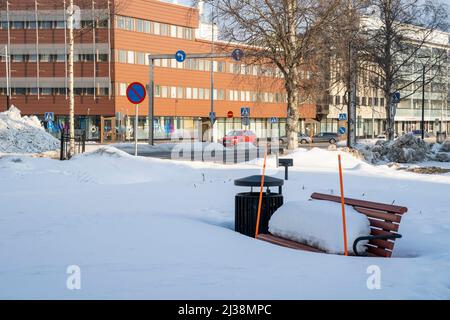 Rovaniemi, Finnland - 17.. März 2022: Eine verschneite Bank an einem sonnigen Wintertag in Rovaniemi, Finnland. Stockfoto