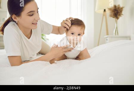 Mama und ein sechs Monate altes Mädchen entspannen, spielen und Spaß haben zusammen in sonnigen Schlafzimmer. Stockfoto