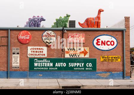 Vintage-Schilder an einer roten Backsteinmauer und Dinosaurier auf dem Dach von Sparky's, einem beliebten Restaurant und Straßenattraktion, und in Hatch, New Mexico. Stockfoto