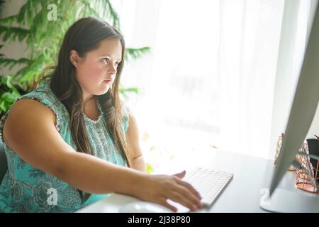 Porträt der Trisomie 21 Erwachsene arbeiten am Computer Stockfoto