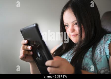 Porträt einer Trisomie 21 Erwachsene, die an einer Tablette arbeiten Stockfoto