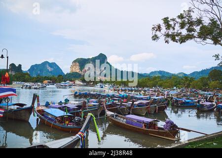 Reisen Sie auf traditionelle Weise. Aufnahme von traditionellen Holzbooten, die an einem Strand in Thailand ruhen. Stockfoto