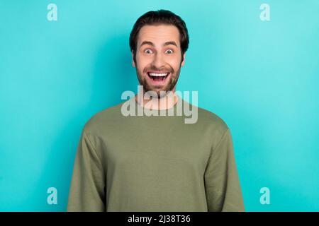 Foto von beeindruckt Brunet jungen Kerl offenen Mund tragen grünes Hemd isoliert auf blauem Hintergrund Stockfoto