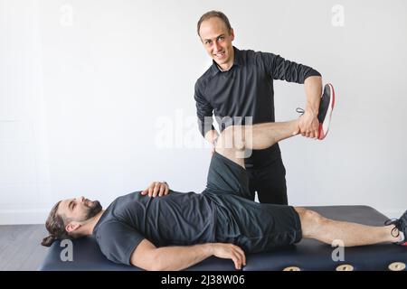 Physiotherapeut, der therapeutische Übungen für den Patienten in der Klinik macht. Stockfoto