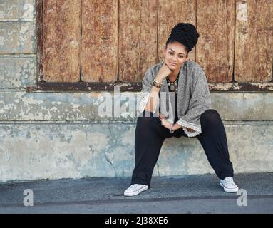 Ändern Sie die Mode, um Sie zu passen. Ganzkörperaufnahme einer modischen jungen Frau, die draußen sitzt. Stockfoto