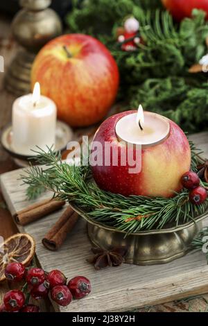 Traditionelle Weihnachtsdekoration mit Äpfeln, Zimtstangen und Kerzen. Festliche Einrichtung Stockfoto